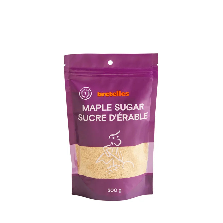 A stand-up pouch of maple sugar from bretelles featuring a purple and gold design with a clear window showing the light brown maple sugar inside.
