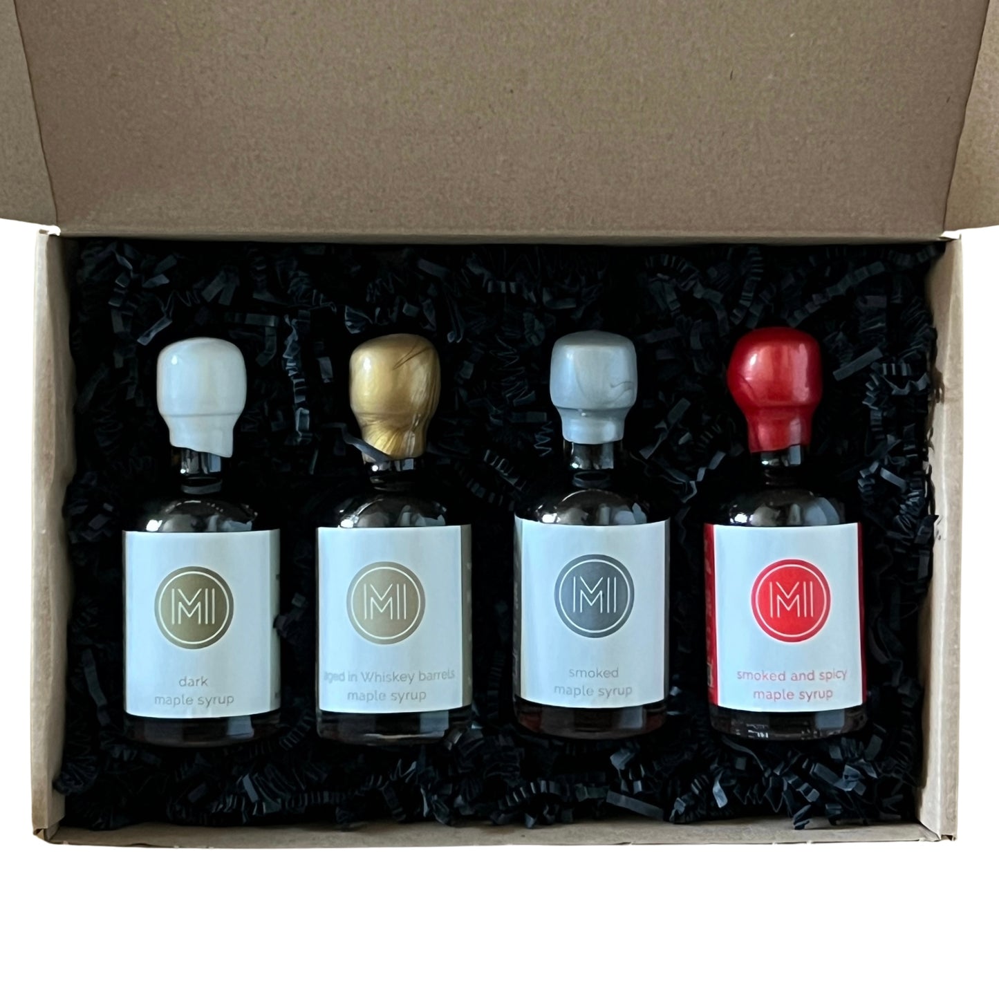 Four small bottles with different colored caps in a box
