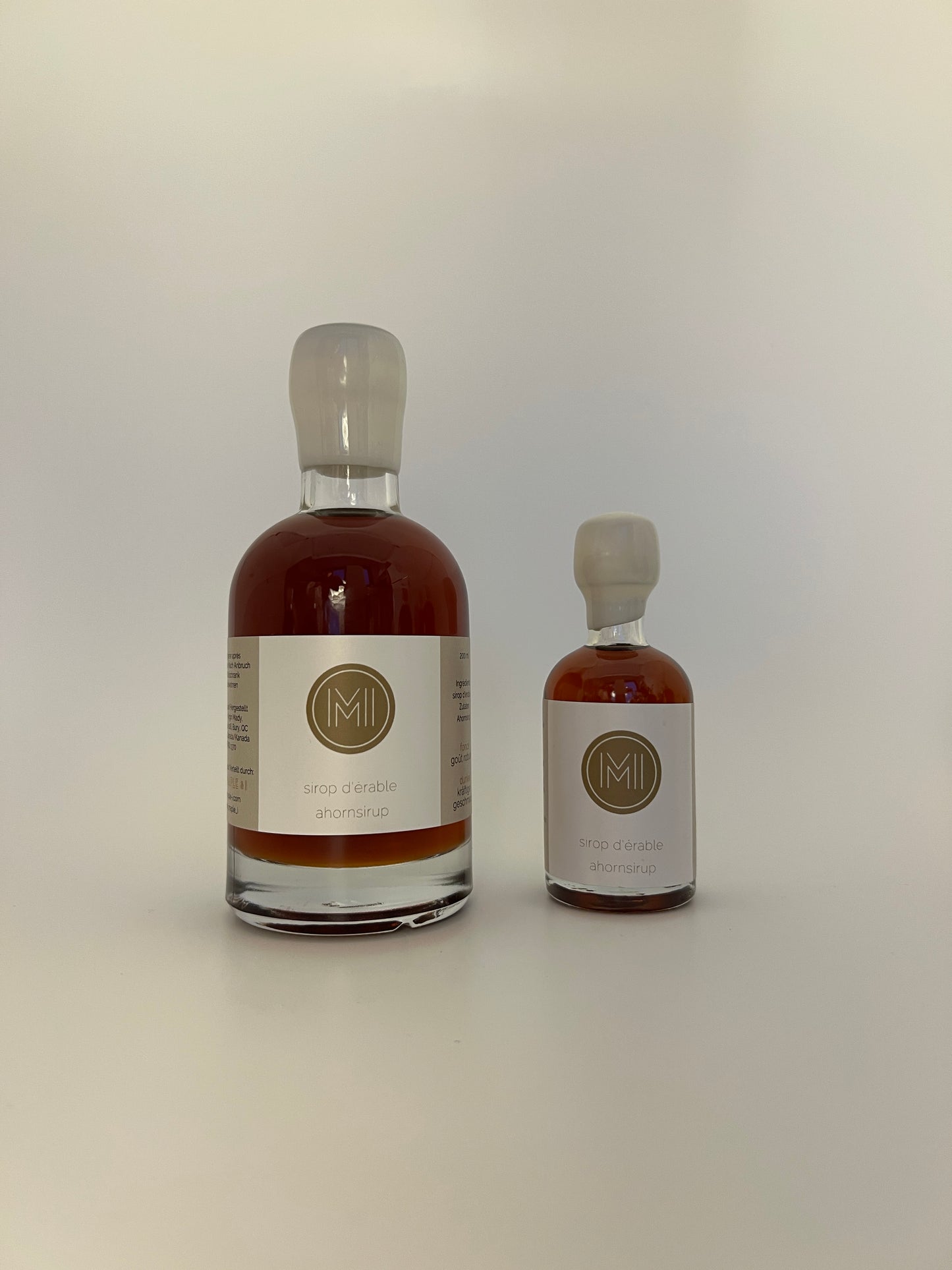 2 side by side bottles of dark maple syrup, one bigger one on the left and a smaller one on the right