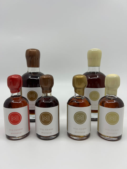 2 rows of specialty maple syrup, 4 small bottles of maple syrup with different seals and logo aligned in the first row and 2 bigger bottle with brown and beige wax seals