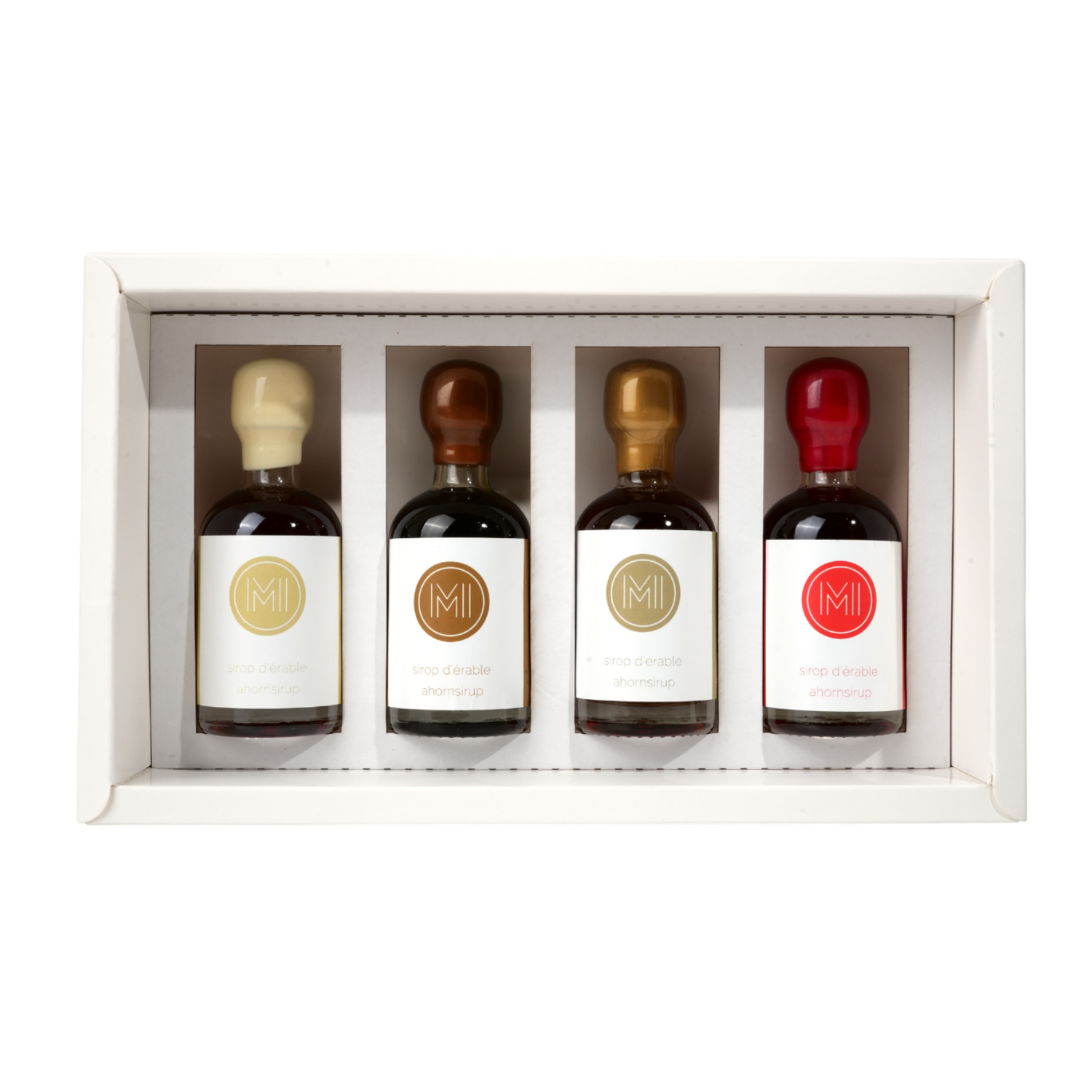 Four maple syrup bottles with different colored caps in a white box on a white background