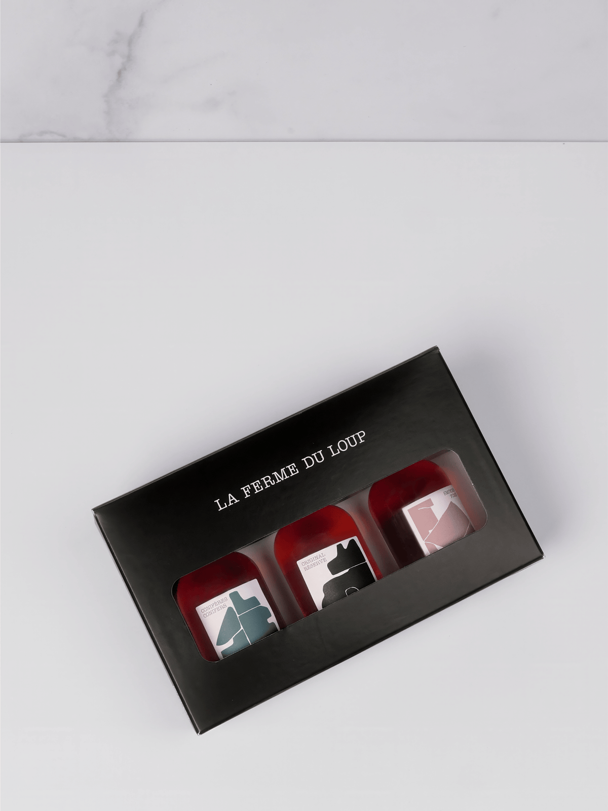 Black gift box with 'La Ferme du Loup' branding containing three small containers on a light gray background.