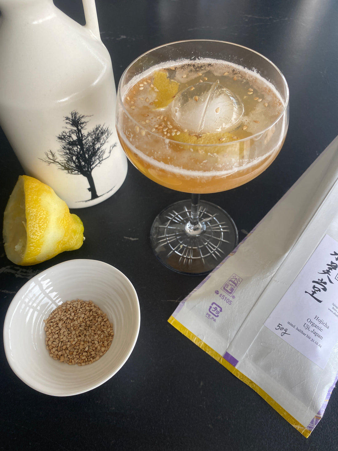 hojicha tea cocktail, sesame seeds and maple syrup bottle