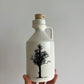hand holding a ceramic jar with a maple tree 
