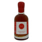 A bottle of smoked and spicy maple syrup with a red cap and a white label featuring a red circular 'MI' logo, set against a plain white background.