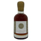 A bottle of aged in Whiskey barrels maple syrup with a light wood cap and a white label featuring a gold, set against a plain white background.