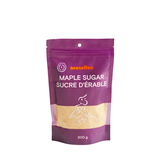 A stand-up pouch of maple sugar from bretelles featuring a purple and gold design with a clear window showing the light brown maple sugar inside.