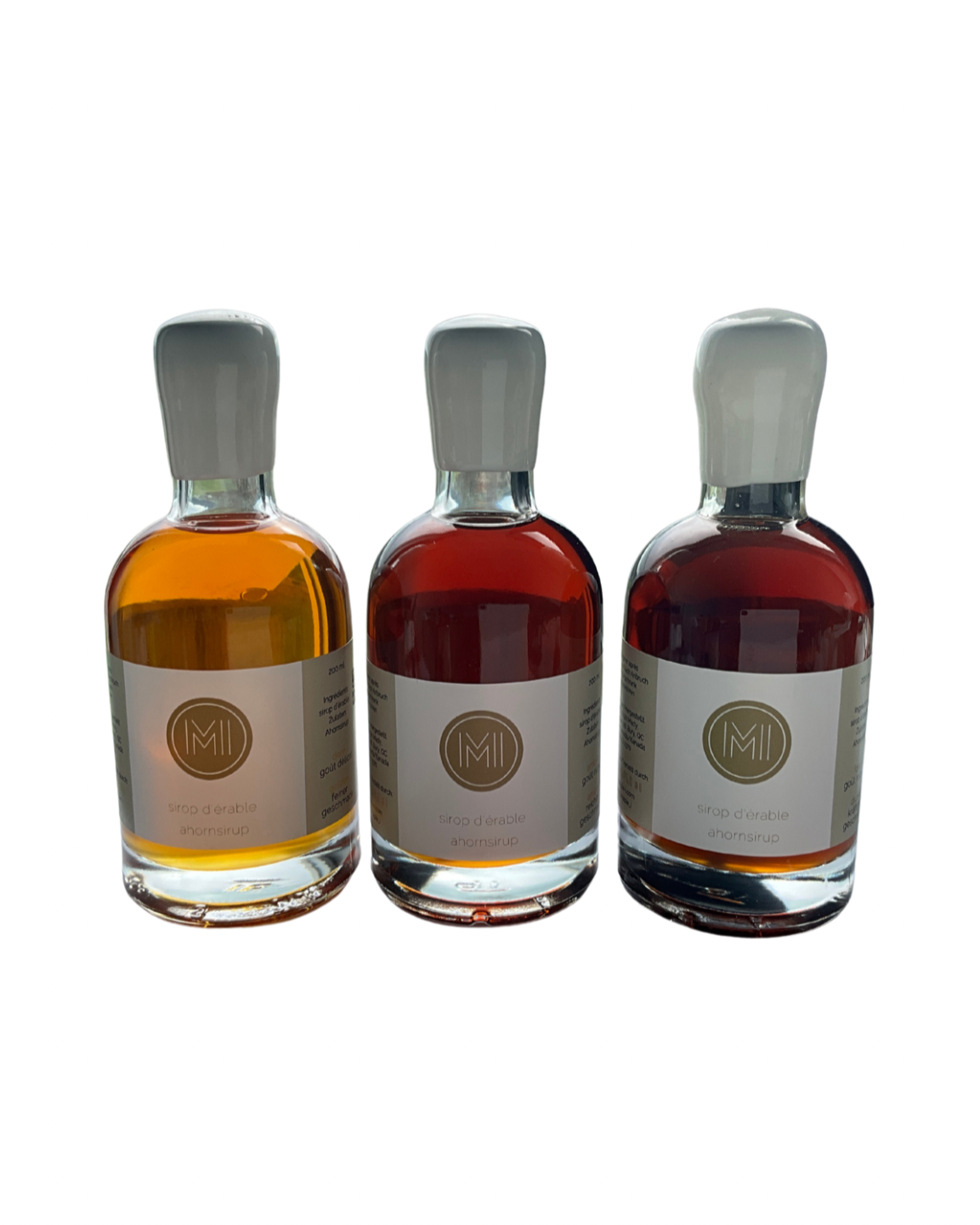 3x200ml side by side bottles of golden, amber and dark maple syrup facing in front with no background