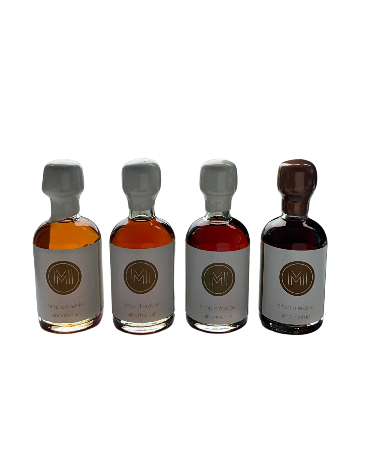 4x50ml side by side bottles of golden, amber, dark and coffee maple syrup  standing with no background
