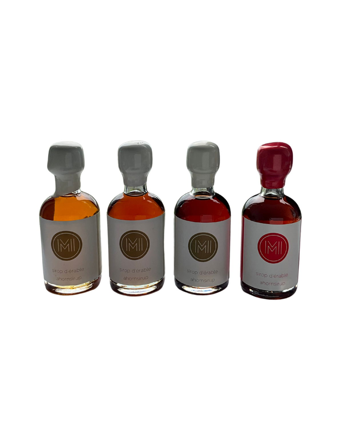 4x50ml side by side bottles of golden, amber, dark and spicy maple syrup  standing with no background