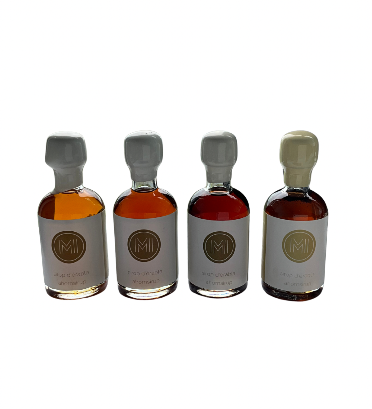 4x50ml side by side bottles of golden, amber, dark and vanilla maple syrup standing with no background