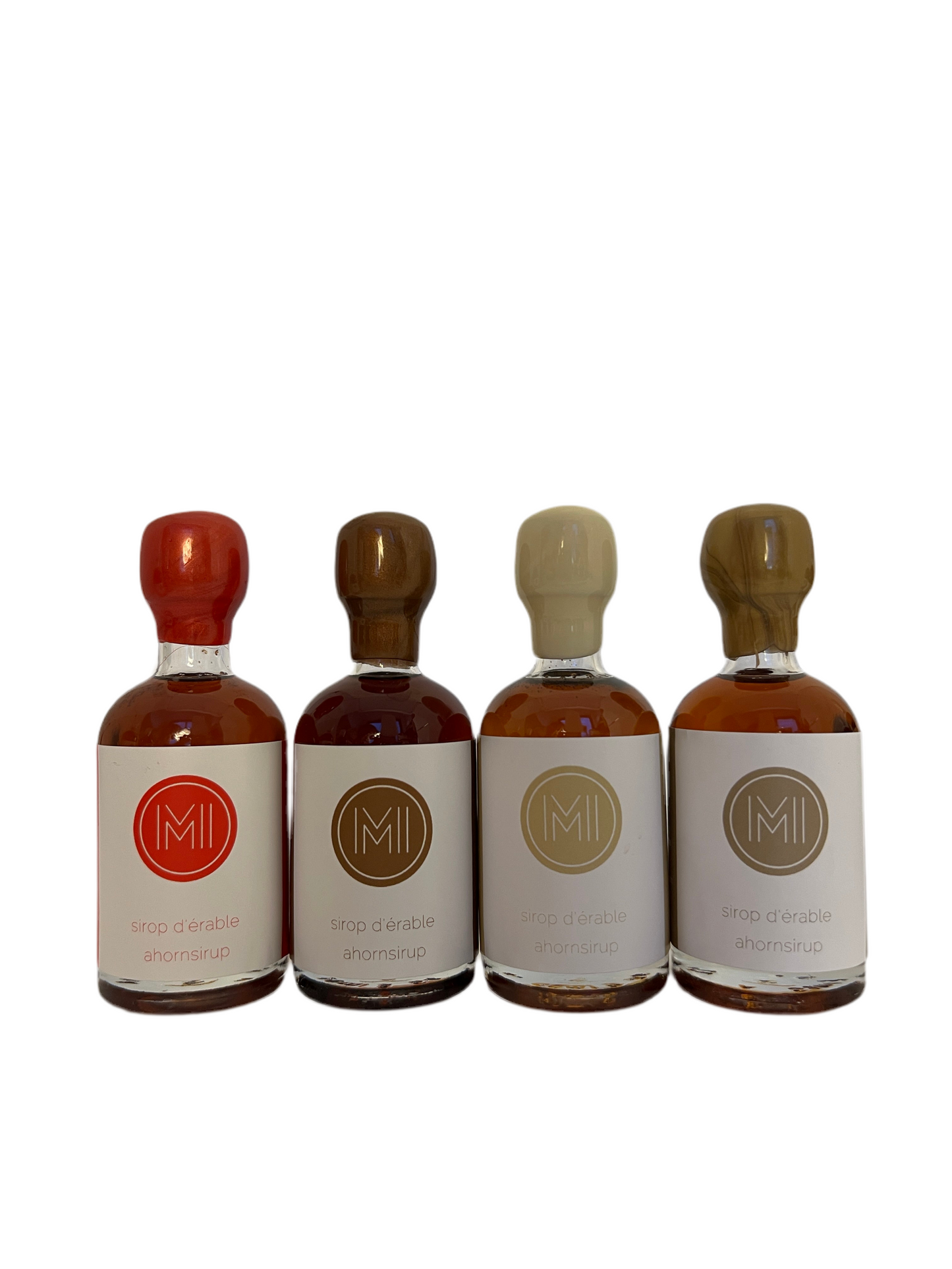 4x50ml side by side bottles of spicy, coffee, vanilla and whiskey maple syrup standing with no background