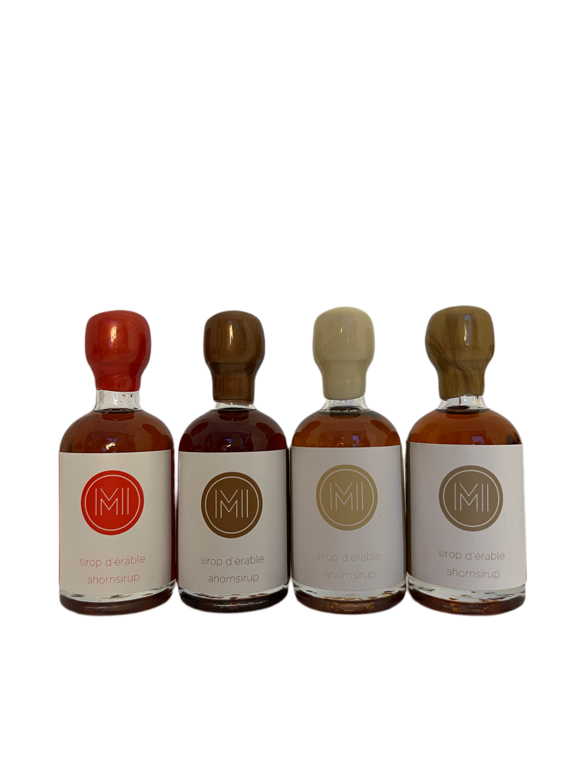 4x50ml side by side bottles of spicy, coffee, vanilla and whiskey maple syrup standing with no background