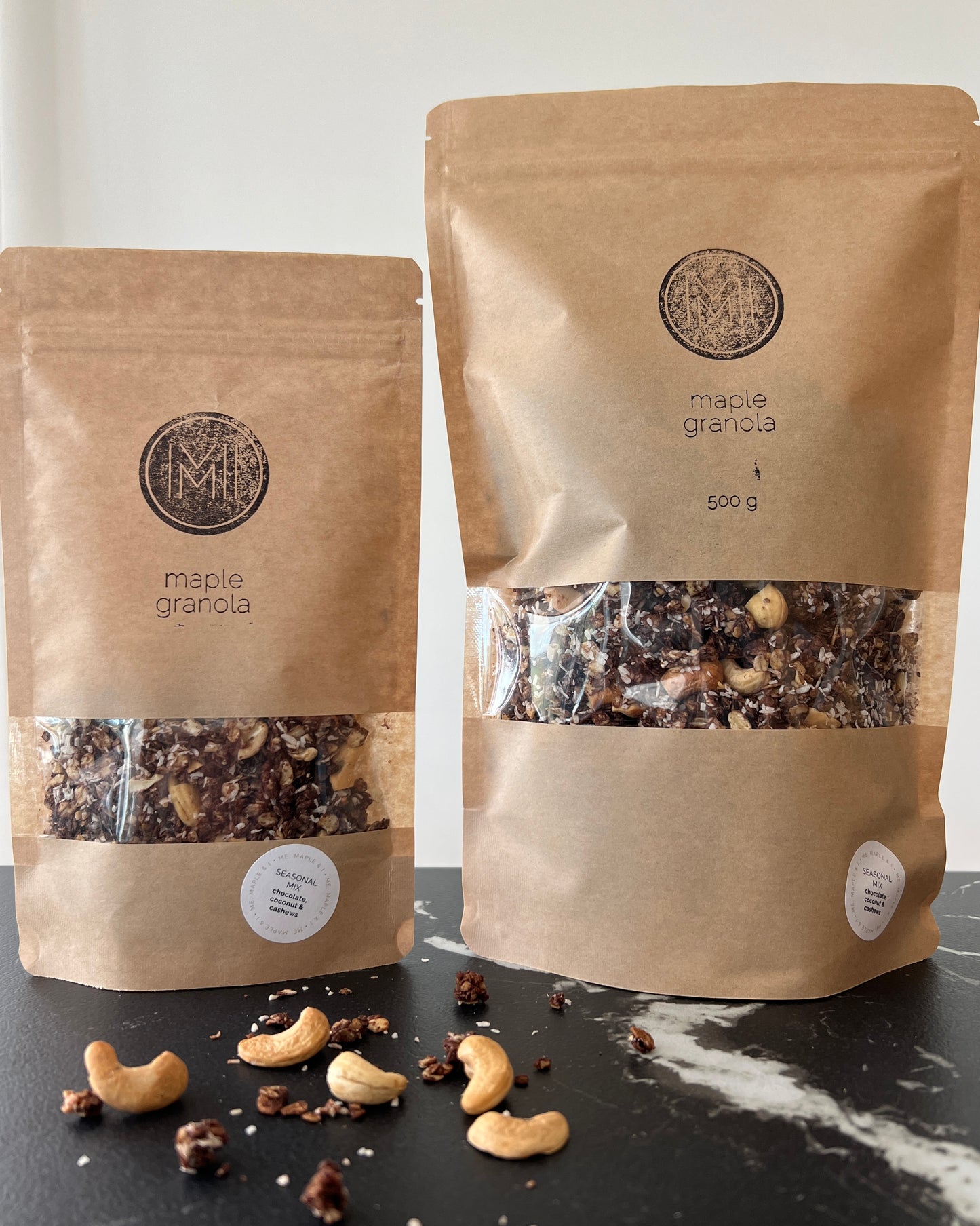 spring - two maple seasonal granola bags with chocolate and cashews side by side on a countertop 