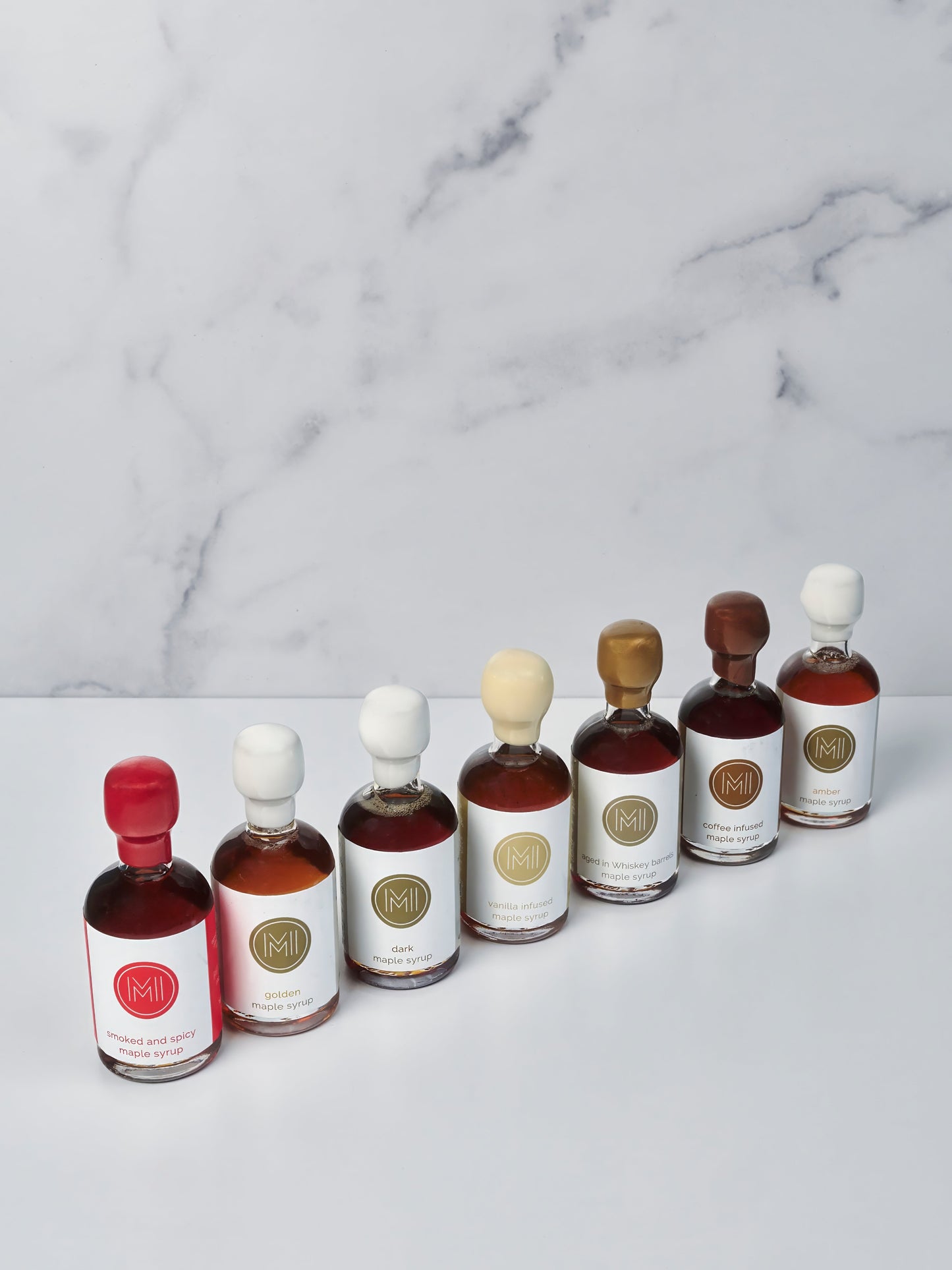 Set of small bottles of maple syrup with labels on a marble surface