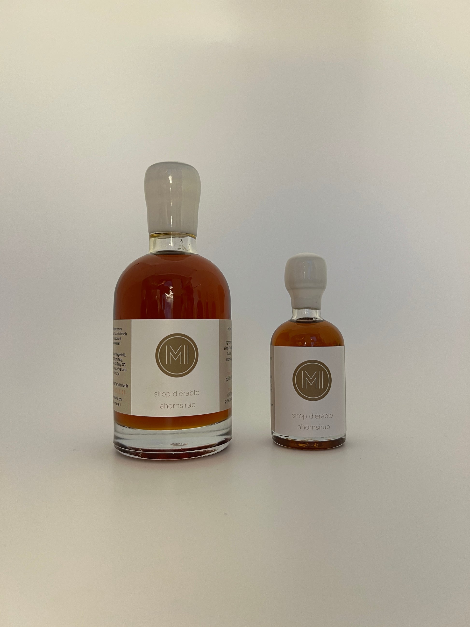 2 side by side bottles of amber maple syrup, one bigger one on the left and a smaller one on the right 