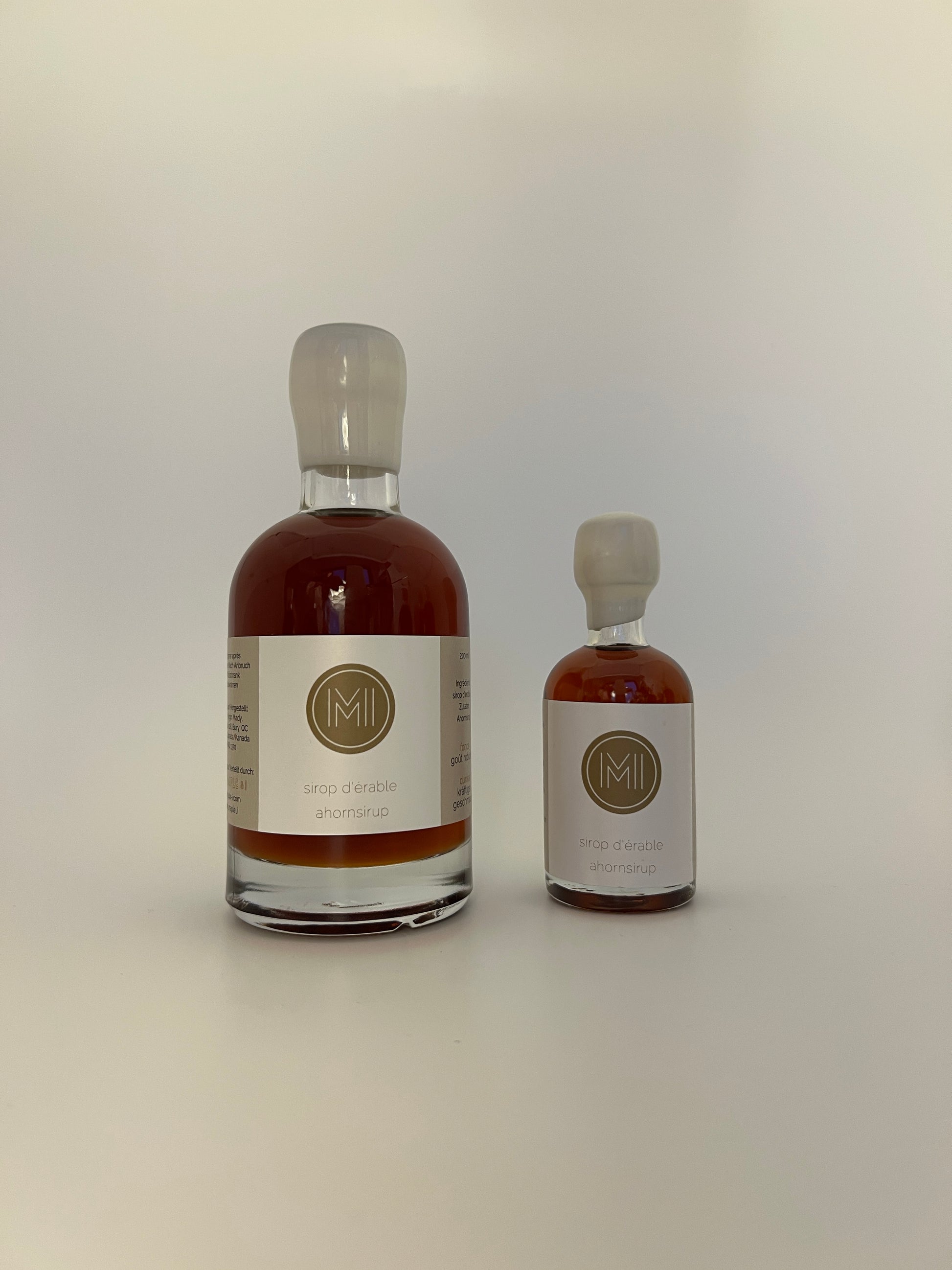 2 side by side bottles of dark maple syrup, one bigger one on the left and a smaller one on the right 