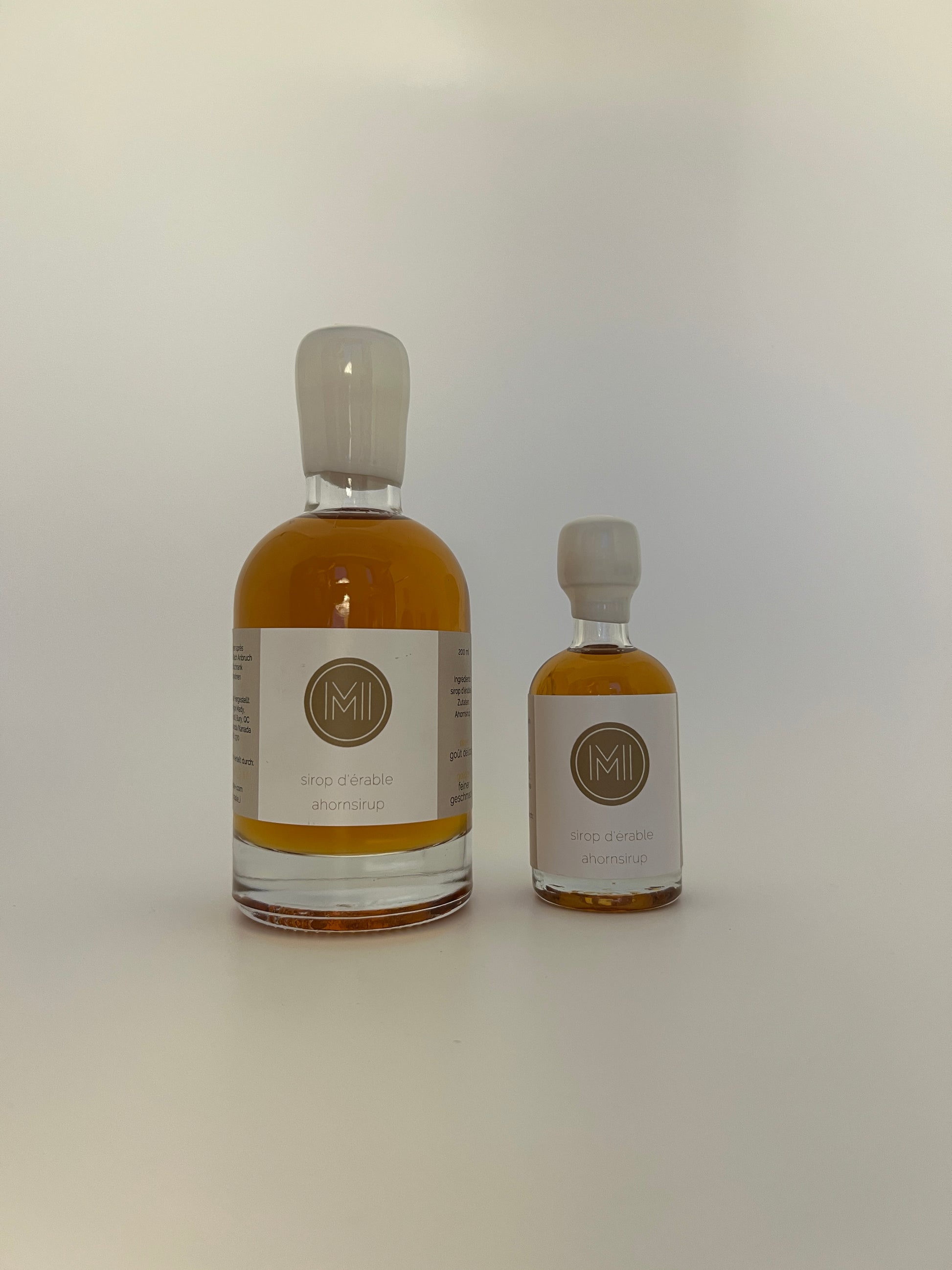 2 side by side bottles of golden maple syrup, one bigger one on the left and a smaller one on the right 