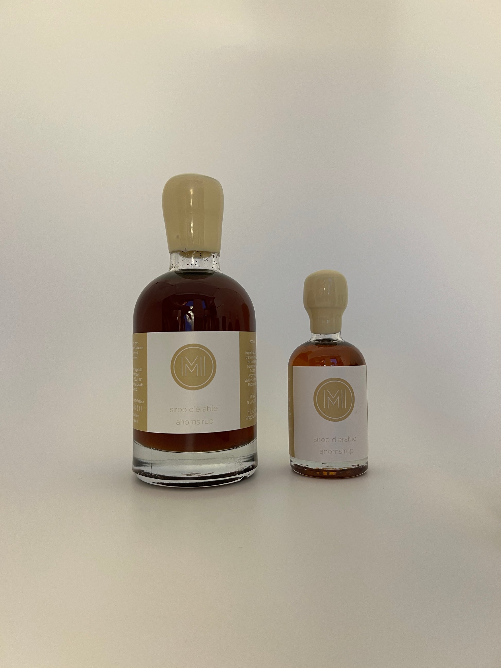 2 side by side bottles of vanilla infused maple syrup, one bigger one on the left and a smaller one on the right 