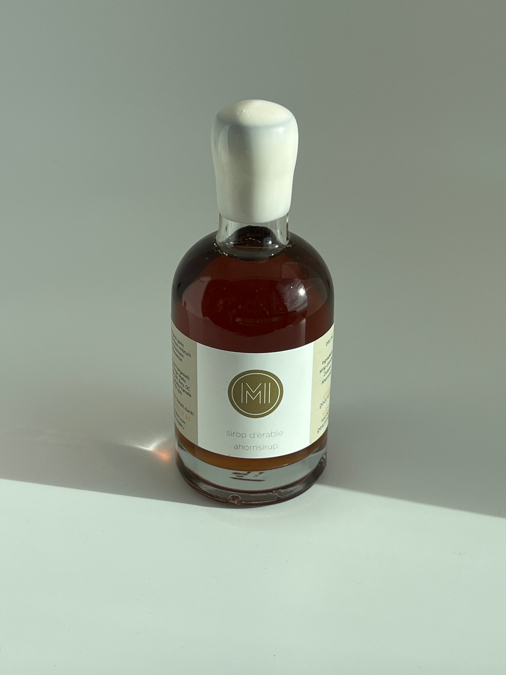 a 200 ml bottle of amber maple syrup with a white wax
