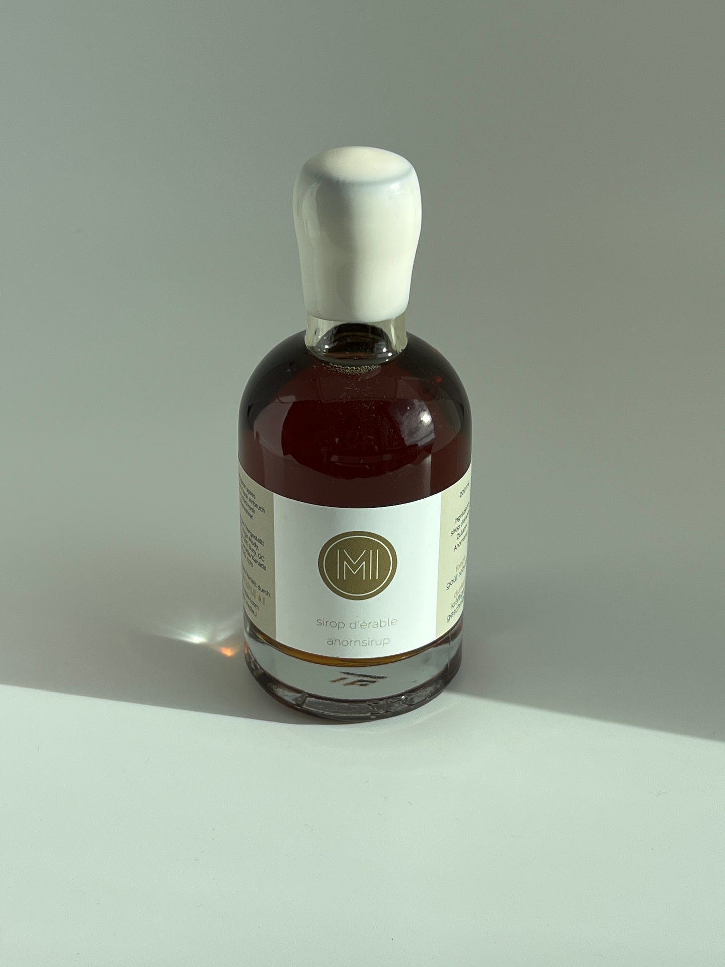 a 200 ml bottle of dark maple syrup with a white wax