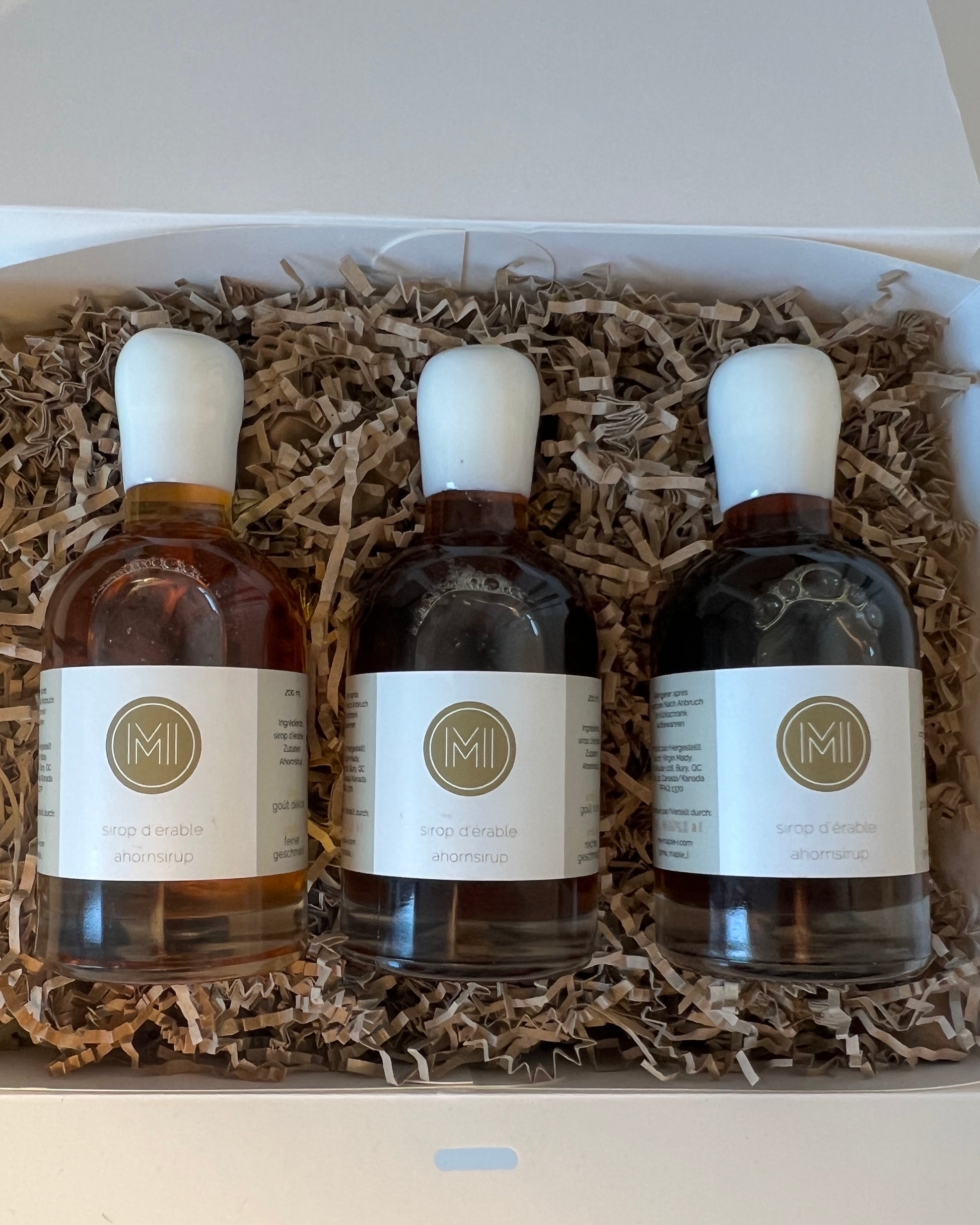 3 side by side 200ml bottles of maple syrup presented in a white box with brown paper straw