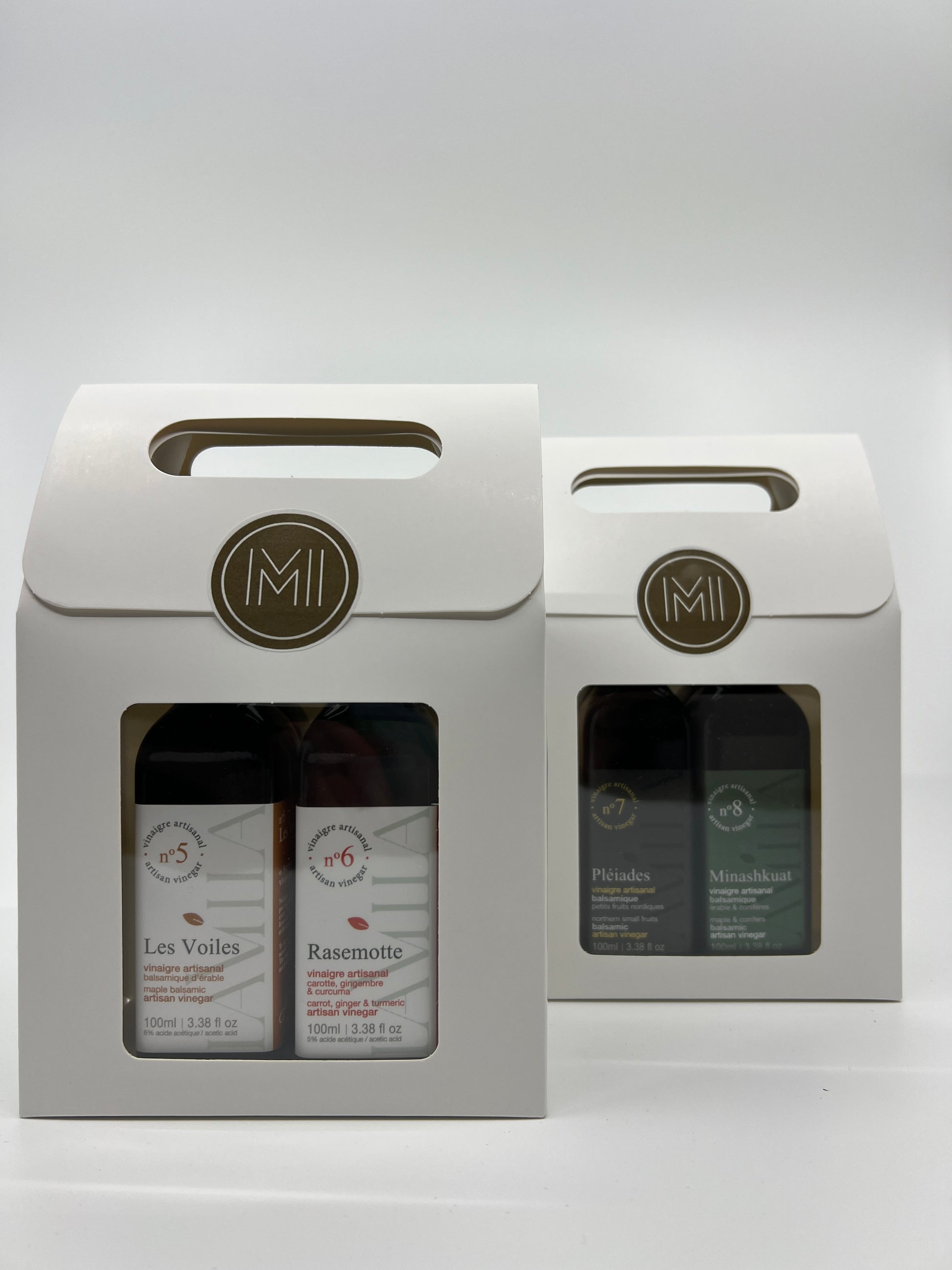 2 discovery sets with each 2 bottles of maple vinegars presented in 2 side by side white paper bag with window showing the products no.5and no.6 in first row 
