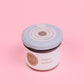 A jar of maple spread taken from the top  on a pink background