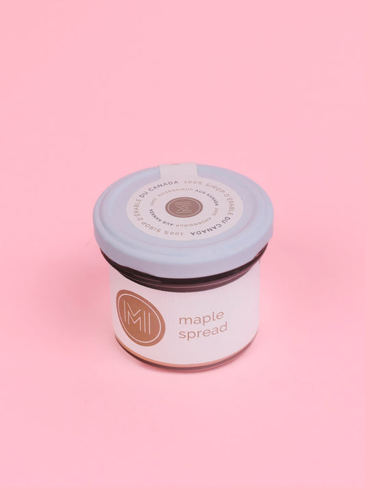 A jar of maple spread taken from the top  on a pink background