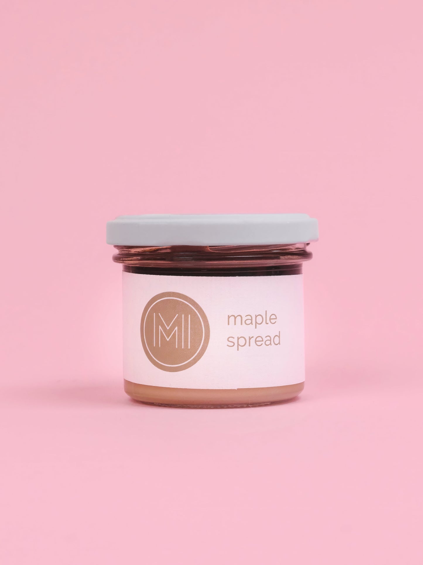A jar of maple spread on a pink background