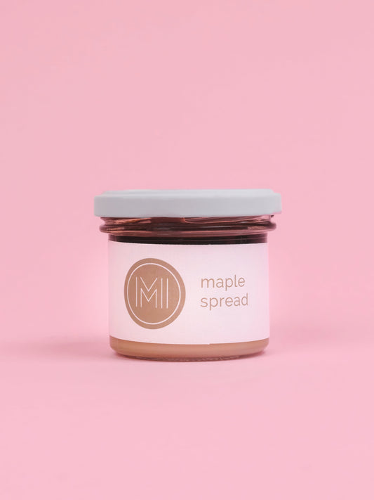 A jar of maple spread on a pink background