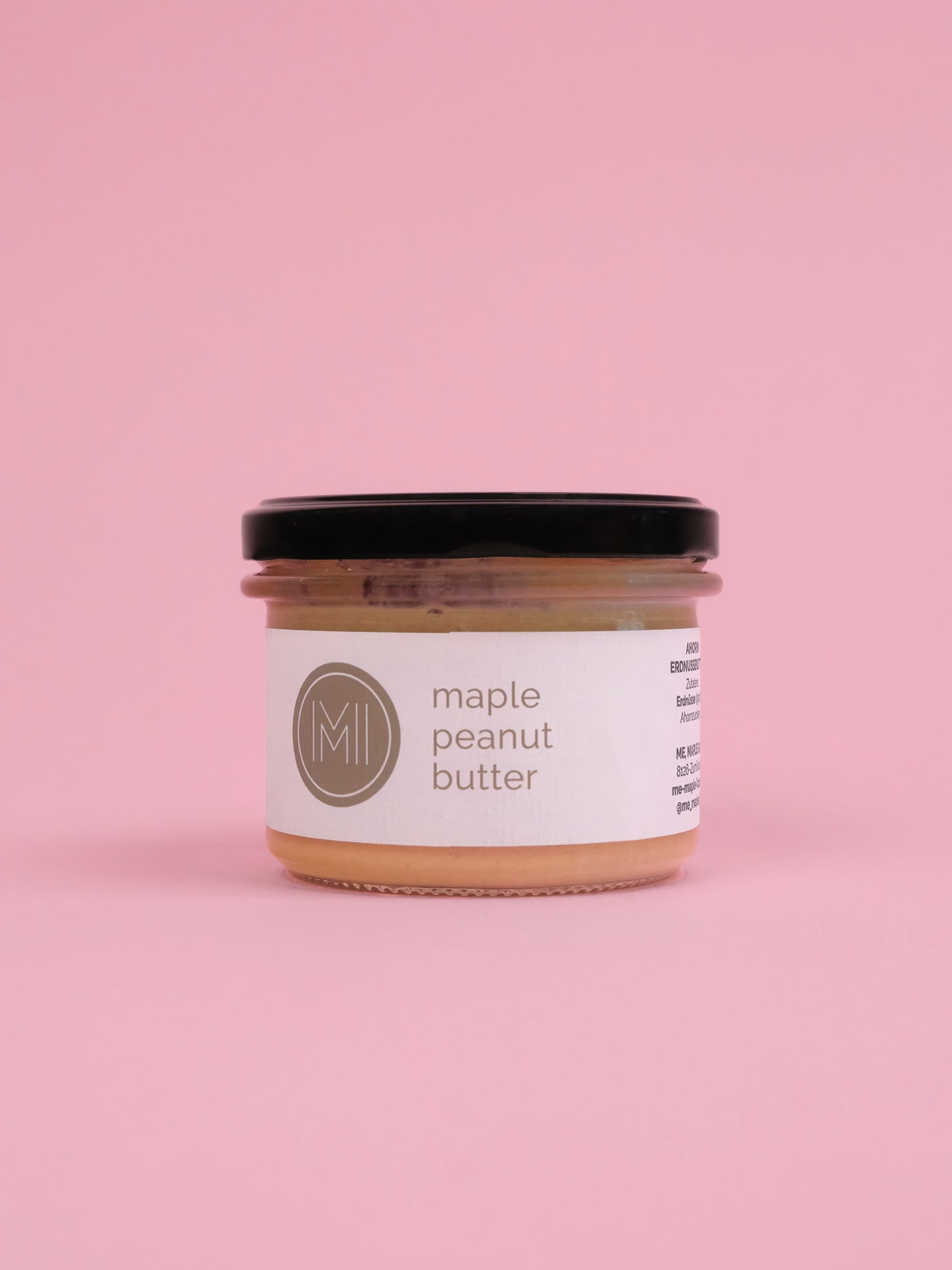 A jar of maple peanut butter on a pink background