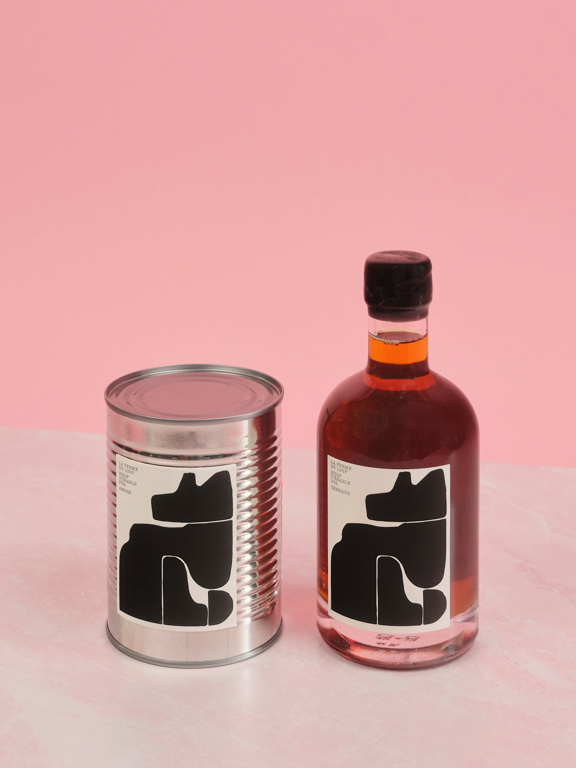 Bottle and can with black silhouette labels on a pink background