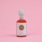 Bottle of amber maple syrup with a white label on a pink background