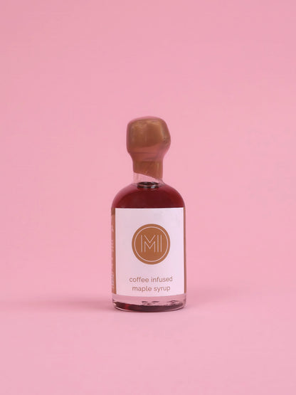 Bottle of coffee-infused maple syrup with a white label on a pink background