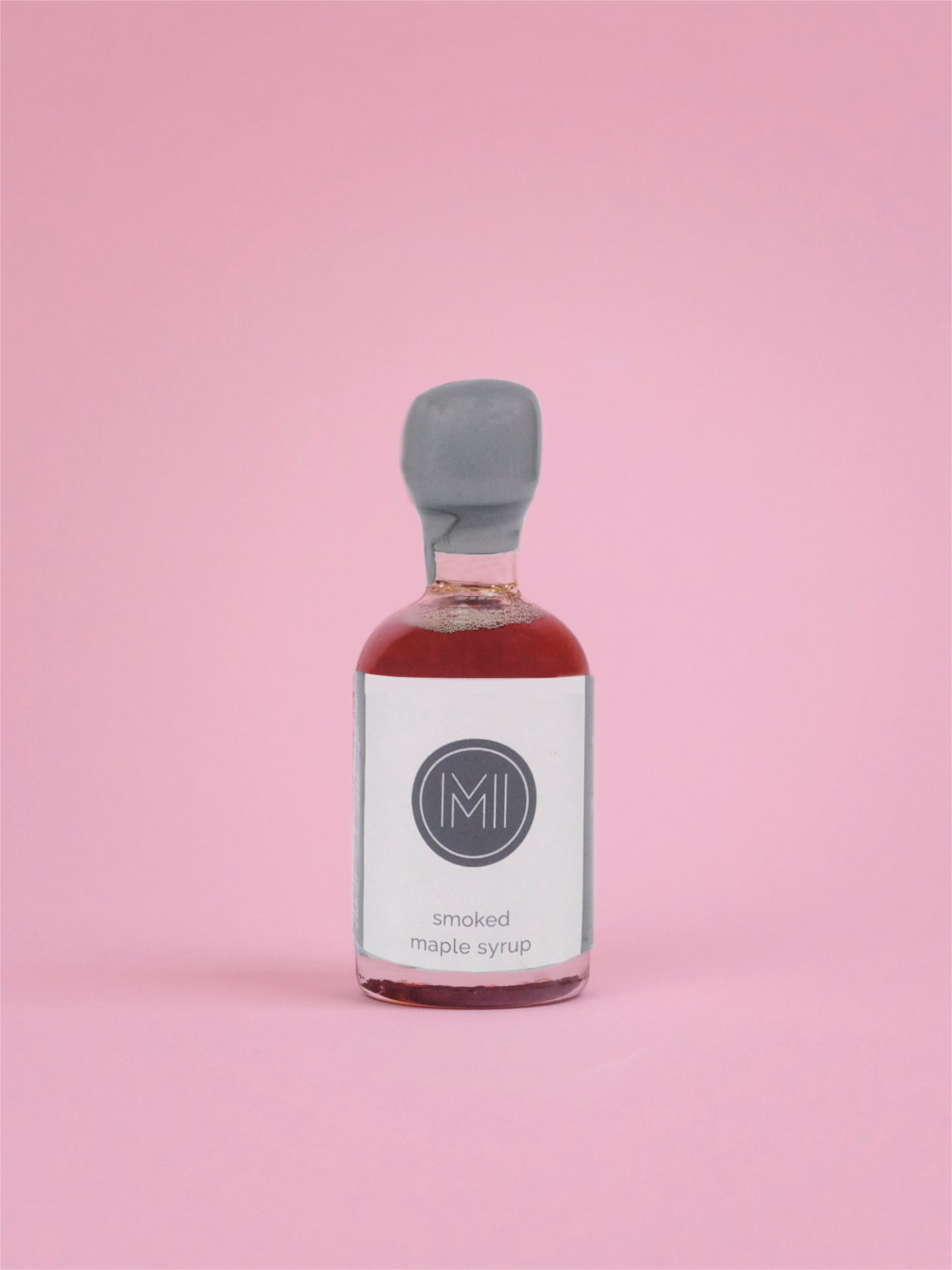 Bottle of smoked maple syrup on a pink background