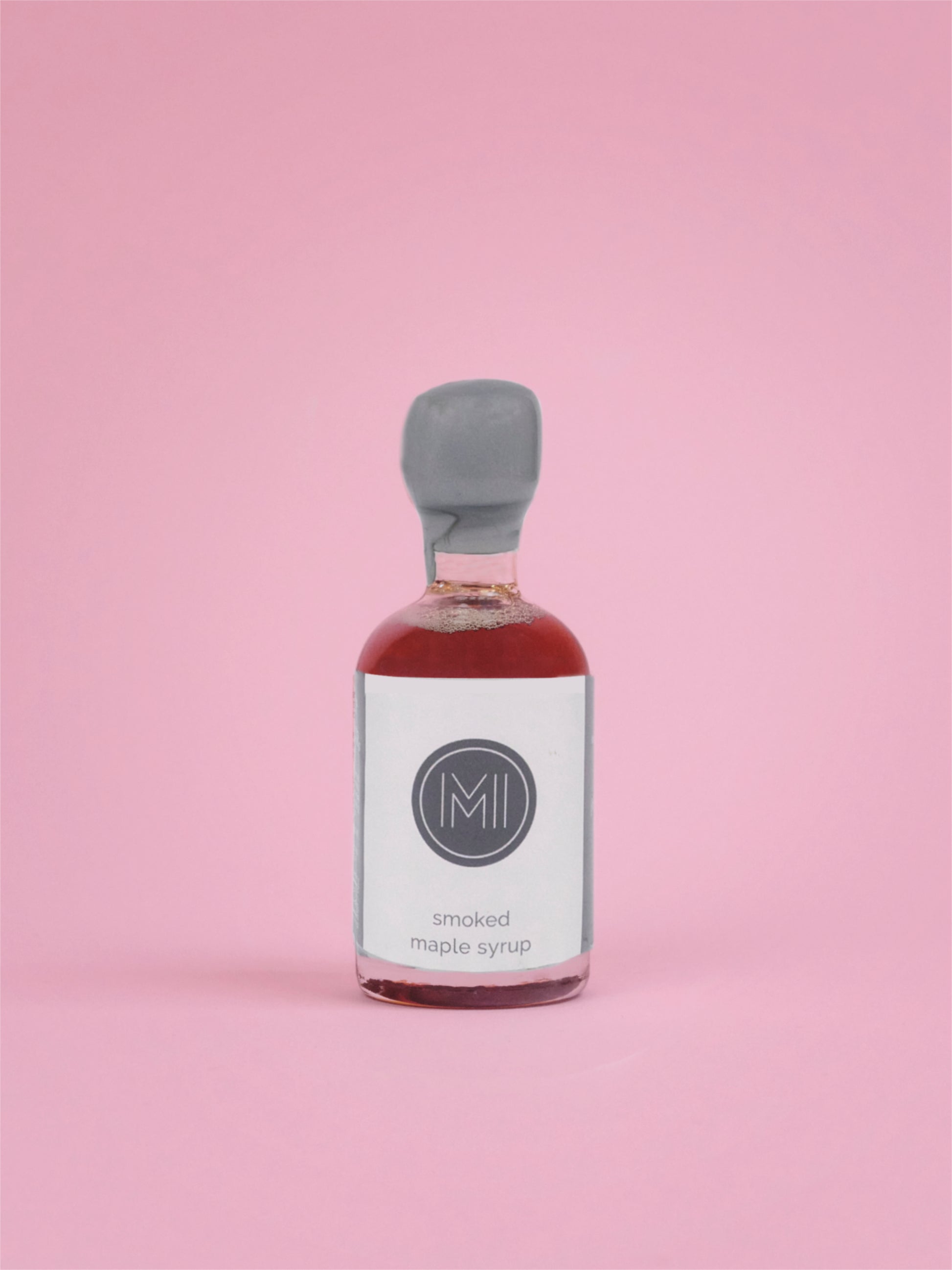 Bottle of smoked maple syrup on a pink background