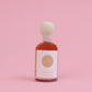 Bottle of vanilla infused maple syrup with a white label on a pink background