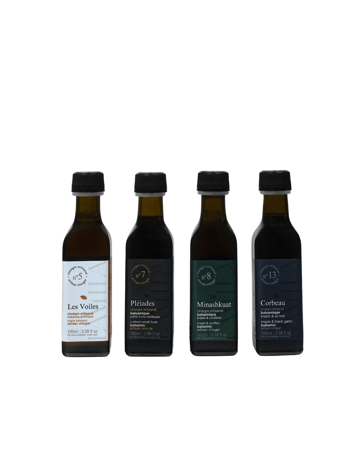 Four small dark glass bottles of olive oil arranged in a row on a plain white background. The labels read Les Voies, Pélades, Mirashasat, and Corbeau.