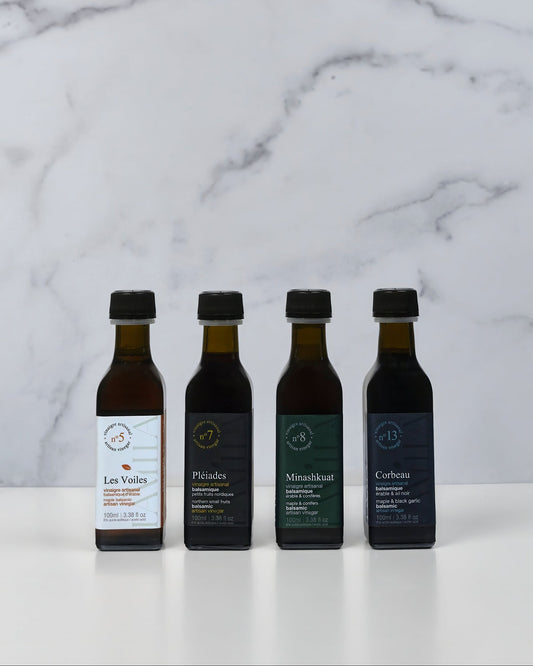 Four bottles of of maple vinegar on a marble surface