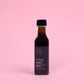 Bottle of maple vinegar Corbeau on a pink background