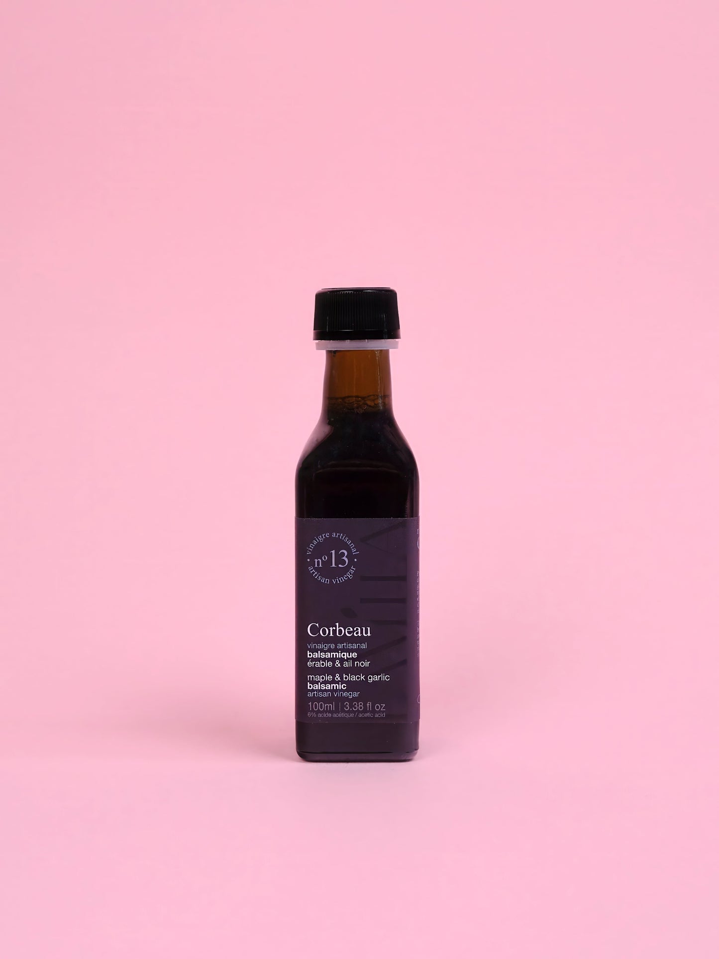 Bottle of maple vinegar Corbeau on a pink background