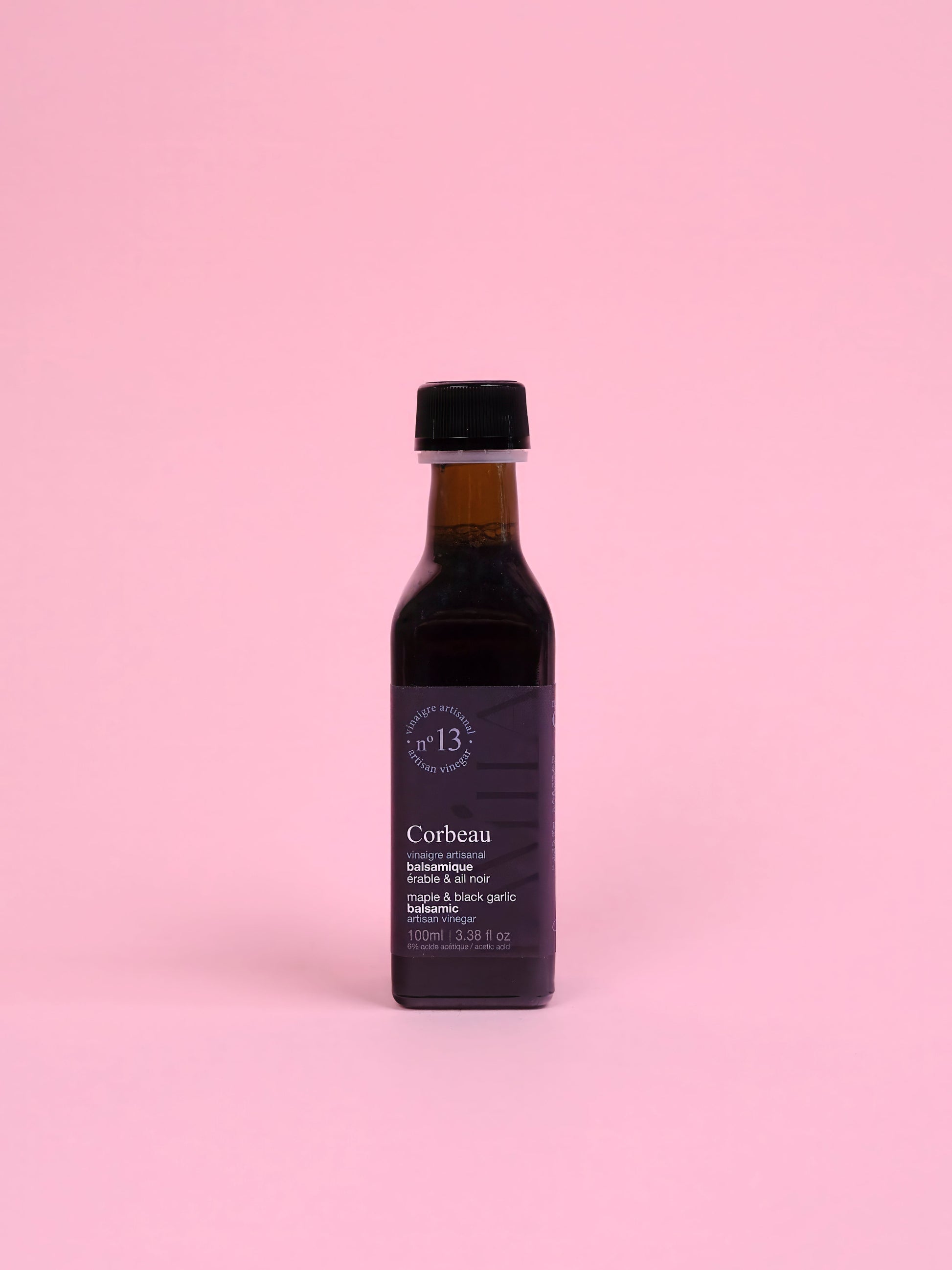 Bottle of maple vinegar Corbeau on a pink background