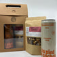 a bottle of 355 ml of amber maple syrup with in second plan a bag of mulled wine spices and in third plan a gif set brown cardboard box with see through window showing a bottle of dark maple syrup and another bag of mulled wine spices.