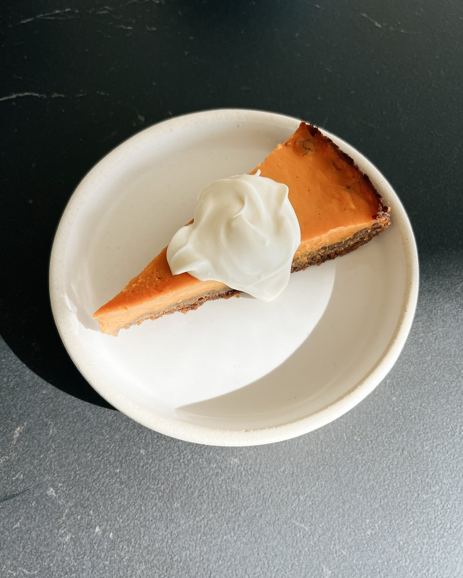 a piee of maple pumpkin pie on a plate with whipped cream