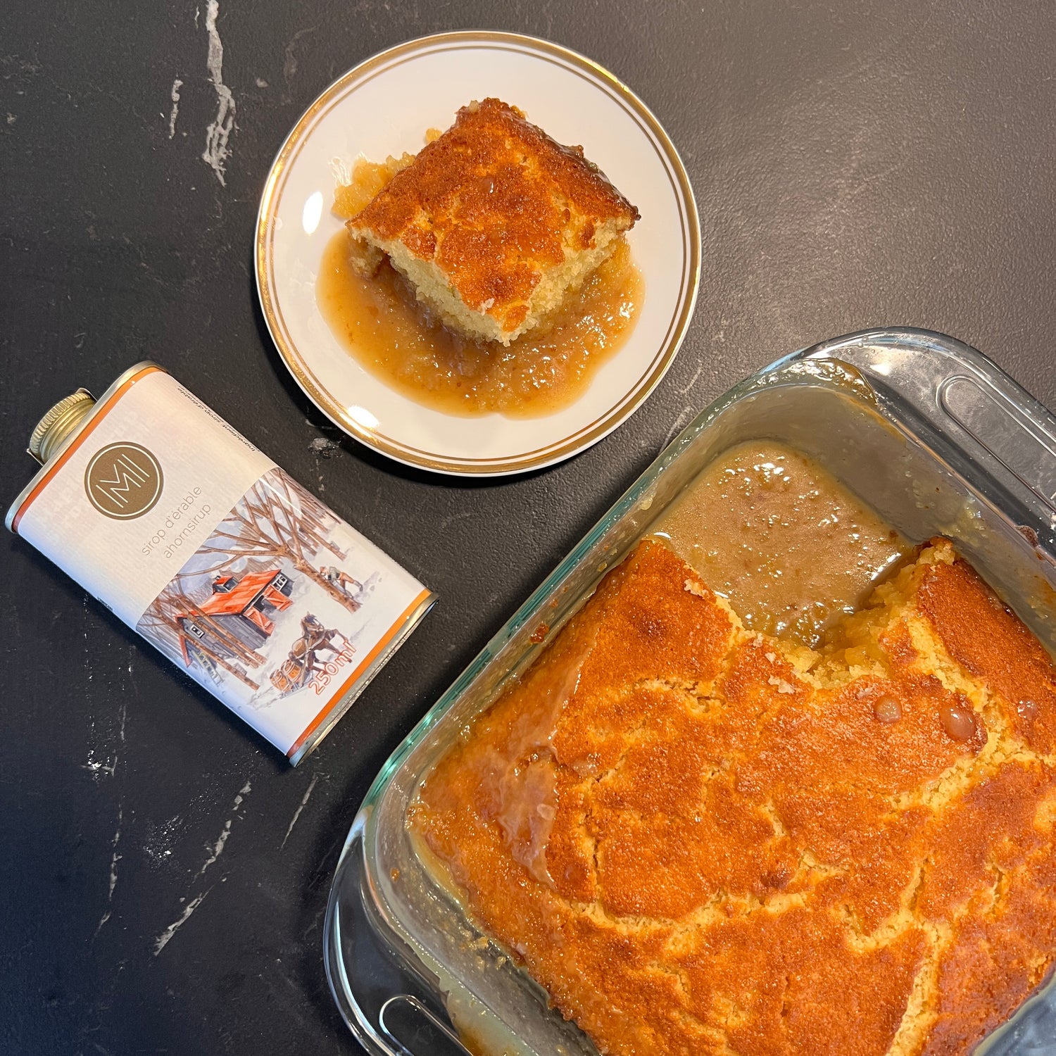 maple pudding cake in a dish, a portion served on a plate and a tin of maple syrup